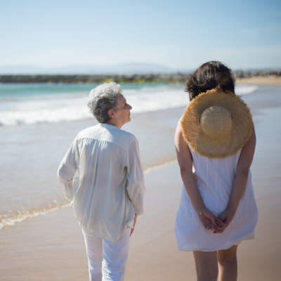 mom and daughter walking on beach